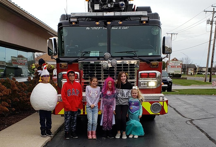 Group of kids in costume in front of fire engine