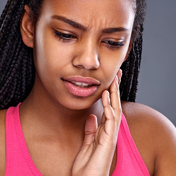 Woman in need of emergency dentistry holding jaw in pain