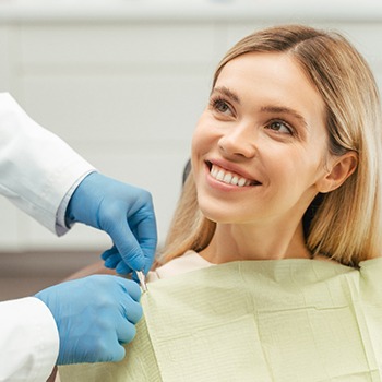 A blond, smiling woman sitting next to her dentist