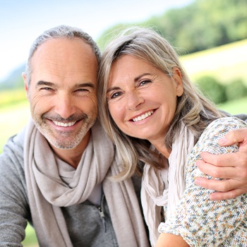 Man and woman smiling after dental implant tooth replacement