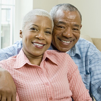 Man and woman smiling after dental implant restoration