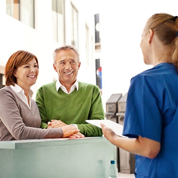 Man and woman discussing the cost of dental implants with dental team member