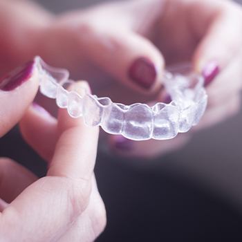 Hand holding an Invisalign tray