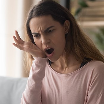 Woman in need of T M J therapy holding jaw in pain