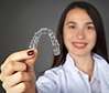 Woman holding up Invisalign tray