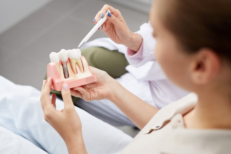 dentist explaining dental implant model