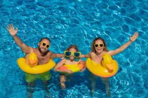 parents and child smiling in the sunlight in pool