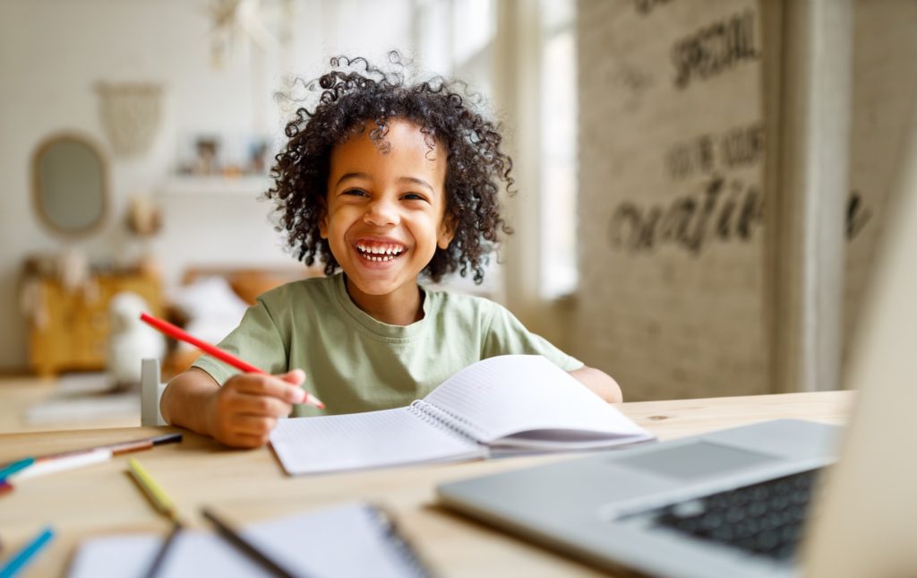 Young boy smiling while working on notebook at home