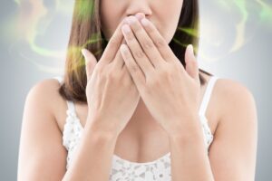 Nose to chest view of a woman with bad breath covering her mouth