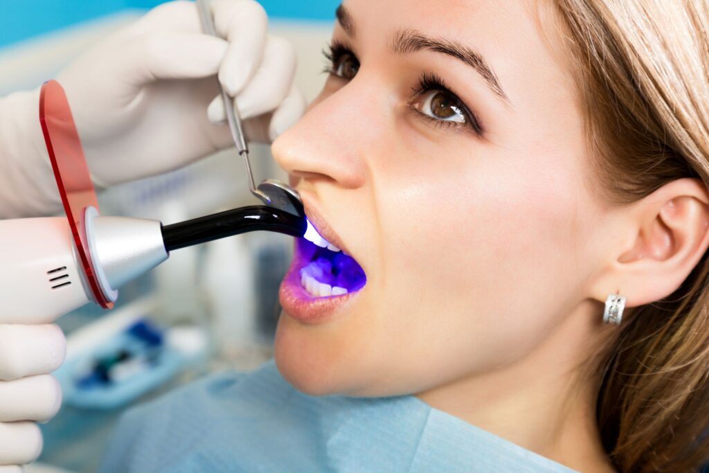 Dentist hardening woman's filling with UV light
